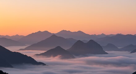 Obraz premium Misty mountain range at sunrise, with soft light and clouds.