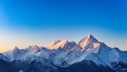 Obraz premium snow covered mountain peaks rise majestically against a clear blue sky as dawn approaches casting soft light on the pristine snow this serene landscape showcases natures beauty
