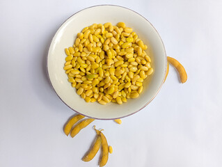 Fresh yellow soybeans in a clear glass bowl on a plain white background. Shiny and neatly arranged beans, perfect for food ingredients, healthy eating, and vegetarian lifestyle concepts.