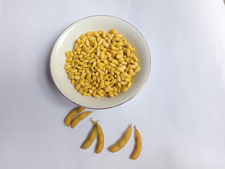 Fresh yellow soybeans in a clear glass bowl on a plain white background. Shiny and neatly arranged beans, perfect for food ingredients, healthy eating, and vegetarian lifestyle concepts.