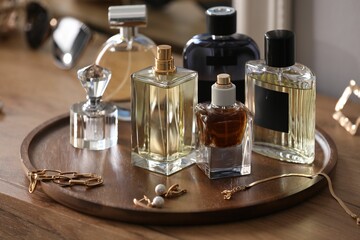 Bottles of different perfumes and accessories on wooden table, closeup