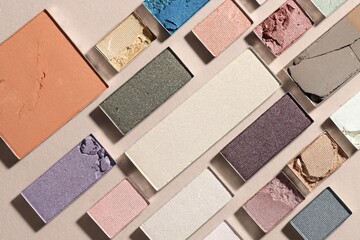 Beautiful eyeshadow refill pans on beige background, flat lay