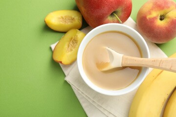 Baby food. Tasty puree in bowl and ingredients on green background, flat lay. Space for text