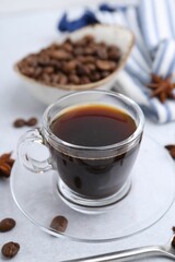 Cup of aromatic coffee, beans and star anise on white table, closeup