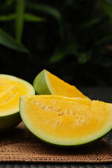 Pieces of ripe yellow watermelon on wicker table, closeup. Space for text