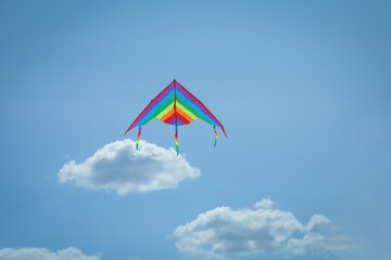 Colorful kite flying in blue sky, low angle view