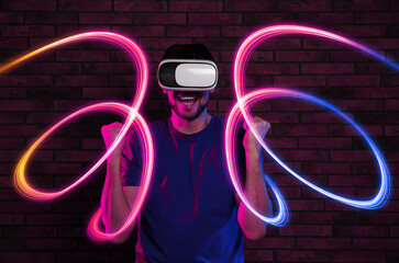 Man using virtual reality headset against brick wall. Bright neon lines around him