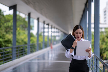 Excited businesswoman reading good news on a document in a modern building