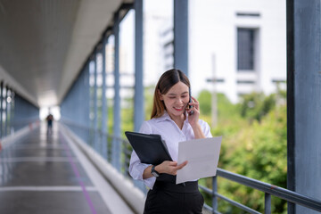 Businesswoman walking and talking on phone while reading documents