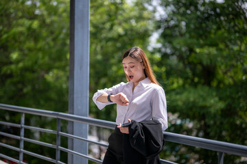 Shocked businesswoman checking time on smartwatch while holding smartphone