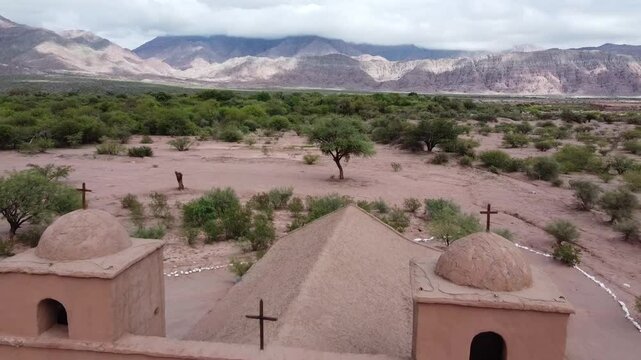 Drone reveals majestic Church Virgen del Rosario de Andacollo in La Falda, Tinogasta, Adobe Route, Catamarca. Its adobe and bell towers emerge from the Andean desert in a cinematic shot.