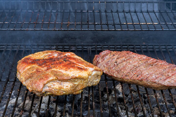Juicy cuts of meat sizzle on grill, releasing mouthwatering aromas as they cook during an outdoor barbecue.