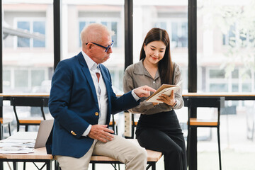 Two business colleagues discussing work on digital tablet in bright modern office, showing...