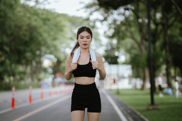 A young woman is jogging outdoors in a park, wearing workout clothes. She is surrounded by nature...