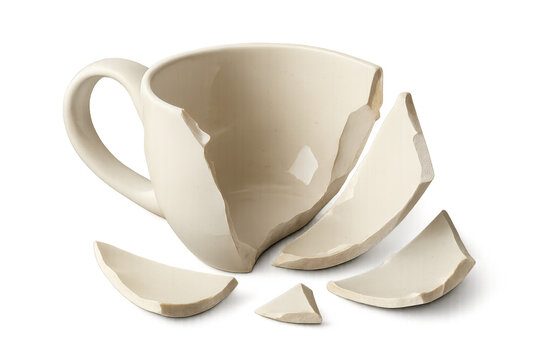 Fractured white ceramic coffee mug lying with scattered fragments, symbolizing vulnerability against transparent backdrop