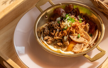 An Egg Skillet served on a dish as breakfast. The eggs are cooked in a cute little pan they are served in, and topped with a variety of meats.