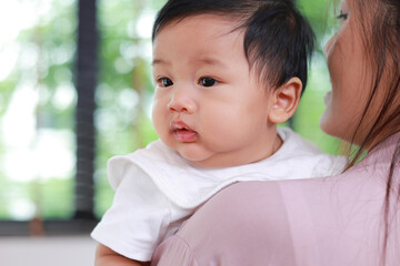 Mother holding her little baby son in her arms. Taking care of newborn to 1 year old. Family concept.