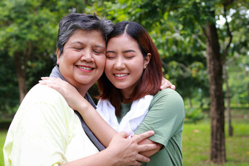 Elderly mother and daughter exercising together in the park, they hug each other and smile happily. Elderly care. Sports concept.