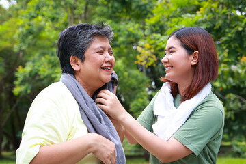 Elderly mother and daughter doing exercise in the park together, they are smiling happily. Elderly care. Sports concept.