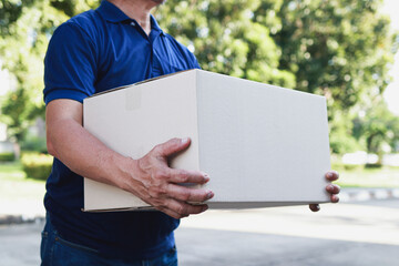 Delivery man wearing blue shirt working in delivery service, holding box to deliver to customer at doorstep. Transporting goods, parcels.