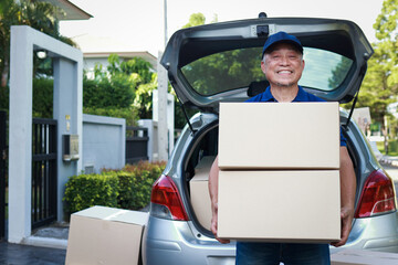 An elderly man in a blue shirt works as a delivery service, holding a box to deliver to a customer at their doorstep. Freight forwarding.