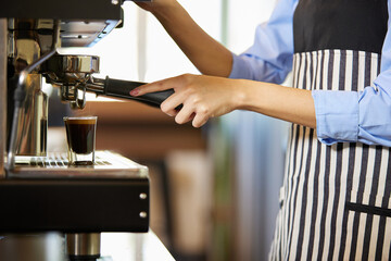 close up barista hands making fresh coffee from machine in the cafe