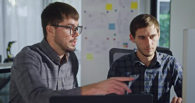 Team adult male engineer collaborate on robotic hand project using AI code solutions machine learning at tech workspace. Artificial intelligence interface, collaboration support prototype development.