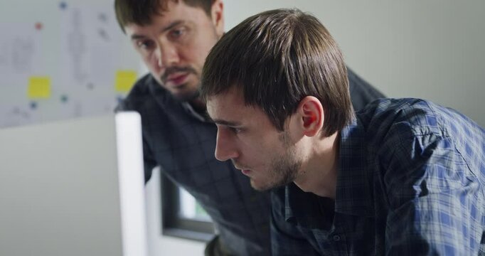 Closeup team adult male engineer collaborate on robotic hand project using AI code solutions machine learning at tech workspace. Artificial intelligence interface, collaboration prototype development.