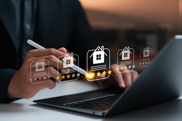 Real estate review rating concept showing businessman using digital pen on laptop to give property five-star rating, smart technology, online service, feedback system, and housing evaluation.