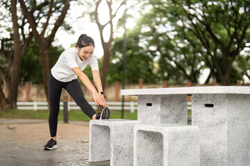 Fitness and Stretching. Young woman stretching at park bench for workout preparation.
