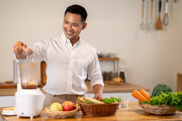 Asian man adding protein powder into a blender while making smoothie drink at kitchen wooden counter