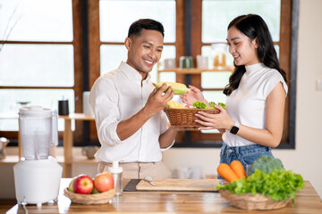 Couple of man and woman holding a basket with fruits and vegetables choosing corn for smoothie drink