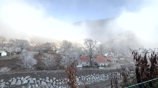 Snow-dusted village homes and trees in misty mountain air of Gabala. Gabala, Azerbaijan