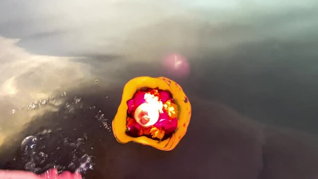 Woman offering floating candle (diya) to holy river Ganga.