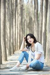 Young Female Sitting Relaxed in Tree-Lined Park Pathway Wearing Casual Outfit