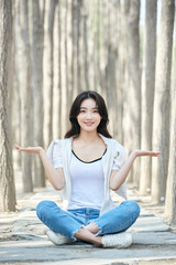 Young Asian female making shrugging gesture while sitting in forest