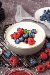 Bowl of tasty semolina porridge with fresh berries on grey background