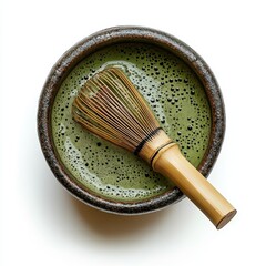 A rustic bowl filled with frothy green matcha tea, accompanied by a traditional bamboo whisk resting inside.