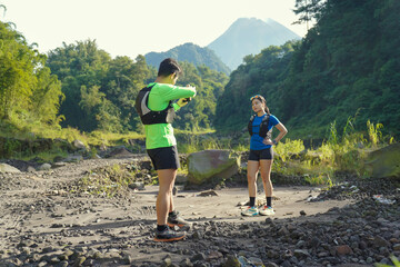 Asian Couple Trail Running and Taking Photos in Lush Nature Landscape