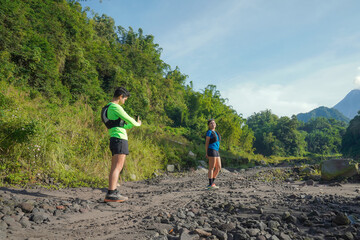 Asian Couple Trail Running and Taking Photos in Lush Nature Landscape