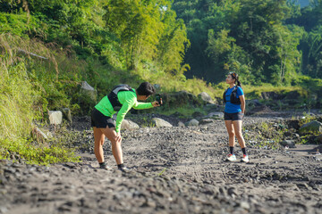 Asian Couple Trail Running and Taking Photos in Lush Nature Landscape