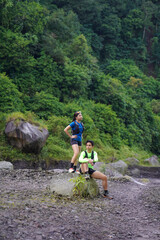 Asian Couple Resting on Trail Run in Rocky Forest Landscape