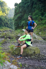 Asian Couple Resting on Trail Run in Rocky Forest Landscape