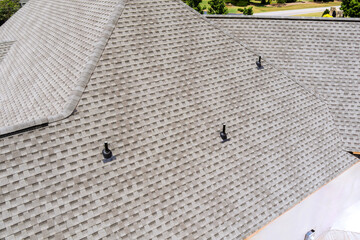 New shingles are being installed on steep sloped residential roof surrounded by overhead.