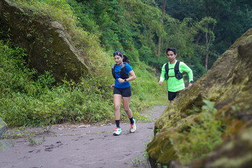 Asian Indonesian couple trail running outdoors, active sustainable lifestyle exercise