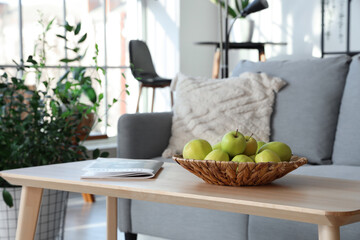Beautiful interior of modern living room with sofa, houseplants and table with apples