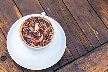 A cup of cappuccino with chocolate powder on a rustic wooden table in Brazil. Perfect for illustrating indulgence, simple pleasures, and coffee culture.