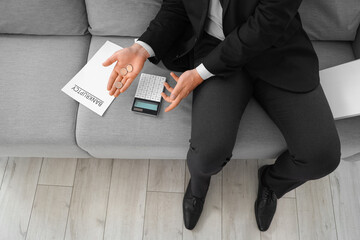 Bankrupt businessman with coins and calculator sitting on sofa in office