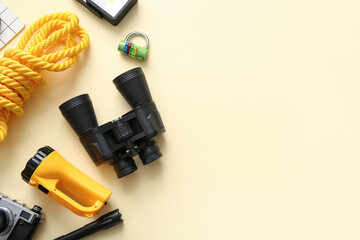 Binoculars and travel items on beige background