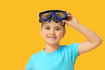 Cute little boy putting swimming mask off on yellow background